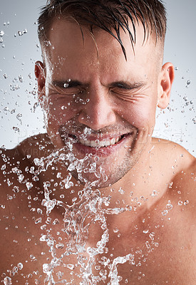 Buy stock photo Water splash, studio and man in shower, smile and morning for washing of body, clean and routine for skincare. Hygiene, happy and person in grey background of bathroom, liquid and relax for bath