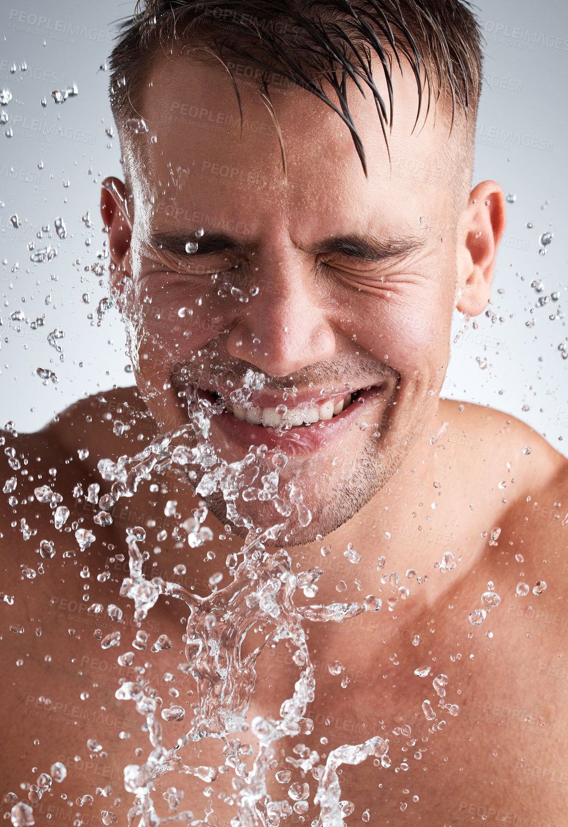 Buy stock photo Water splash, studio and man in shower, smile and morning for washing of body, clean and routine for skincare. Hygiene, happy and person in grey background of bathroom, liquid and relax for bath