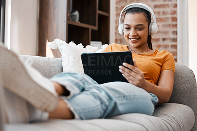 Buy stock photo Shot of a young woman relaxing while using a digital tablet at home