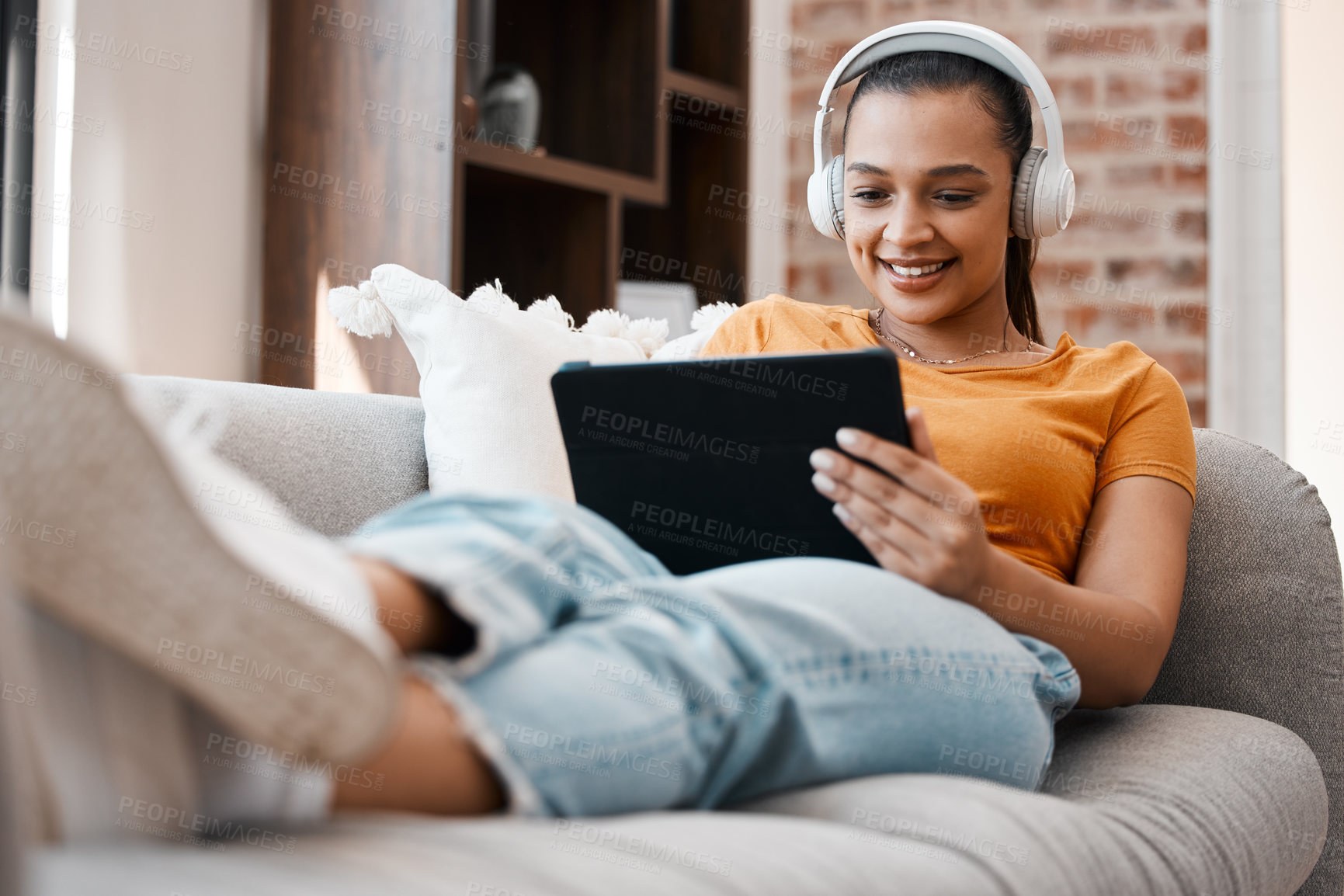 Buy stock photo Shot of a young woman relaxing while using a digital tablet at home