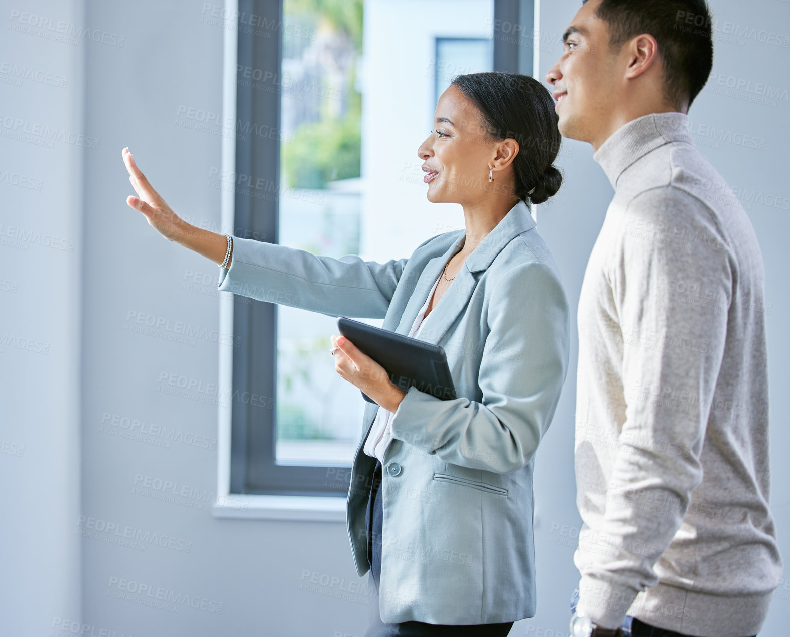 Buy stock photo Shot of a young female real estate agent showing a client a house