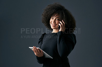 Buy stock photo Shot of a young businesswoman using her smartphone and digital tablet against a studio background