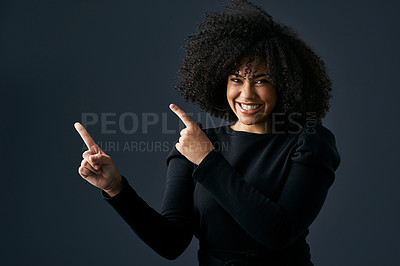 Buy stock photo Shot of a young woman pointing against a studio background