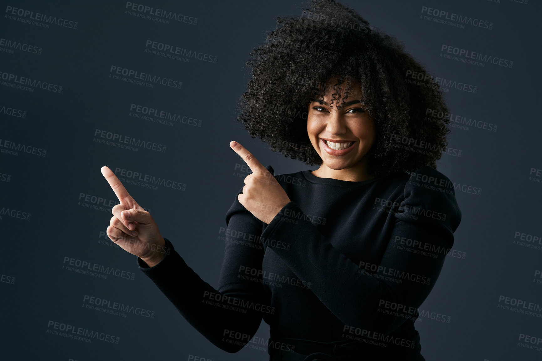 Buy stock photo Shot of a young woman pointing against a studio background