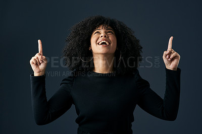 Buy stock photo Shot of a young businesswoman pointing upwards against a studio background