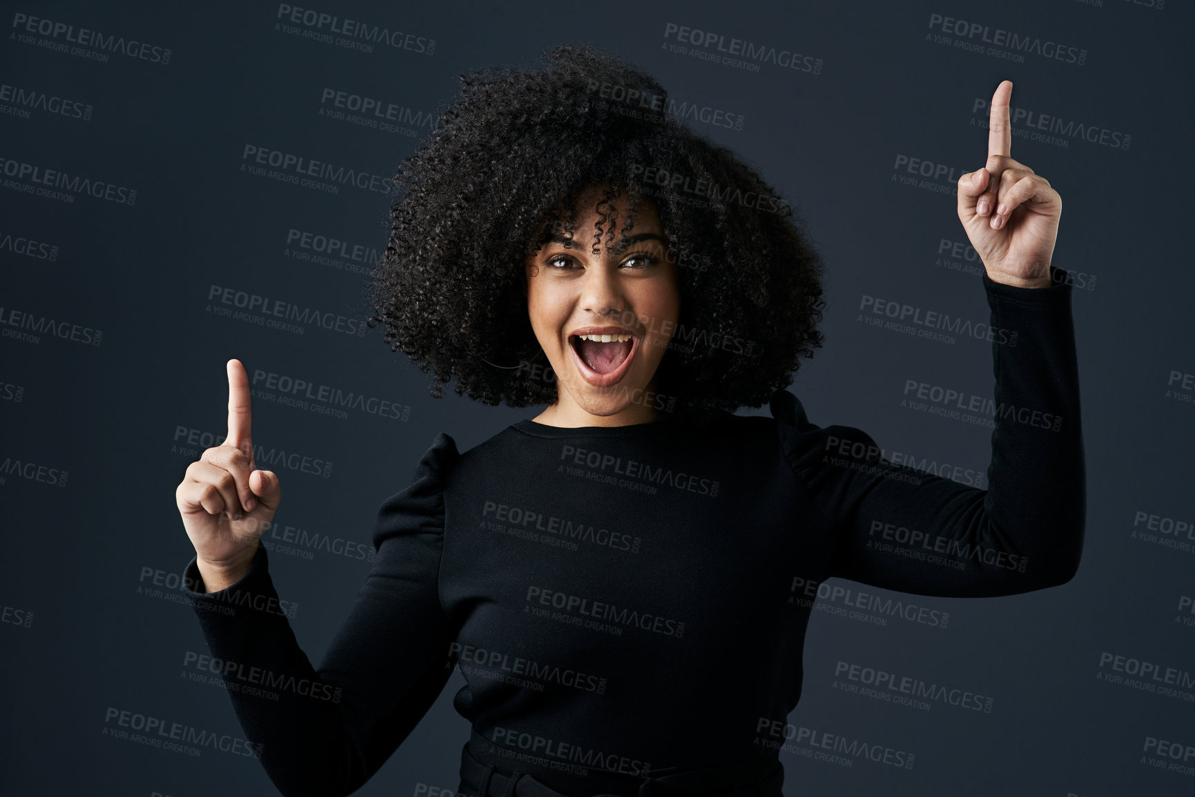 Buy stock photo Shot of a young businesswoman pointing upwards against a studio background