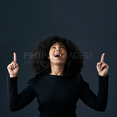 Buy stock photo Shot of a young businesswoman pointing upwards against a studio background