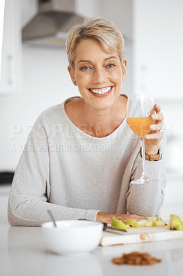 Buy stock photo Shot of a woman holding a glass of juice in her kitchen