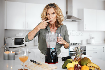 Buy stock photo Shot of a woman tasting her smoothie before serving it