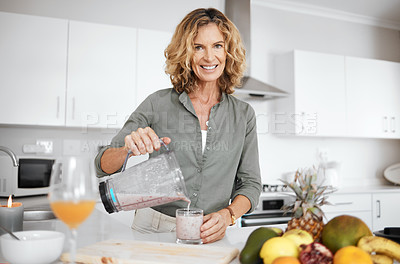 Buy stock photo Shot of a woman pouring her smoothie into a glass