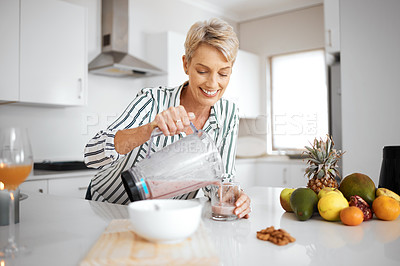 Buy stock photo Shot of a woman pouring her smoothie into a glass