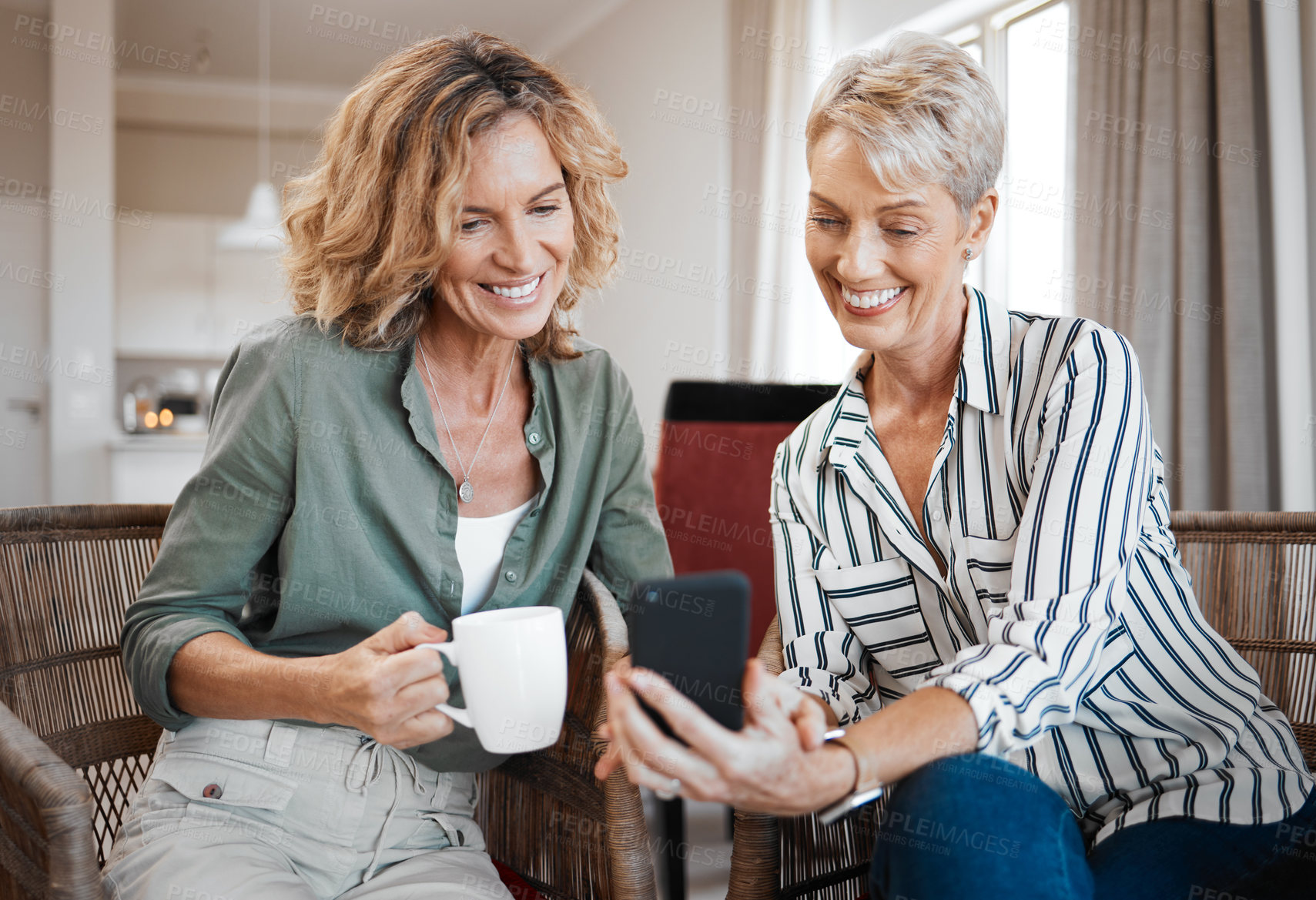 Buy stock photo Shot of two female friends drinking coffee while using a digital tablet