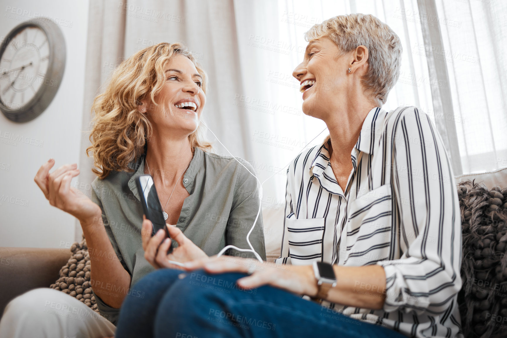 Buy stock photo Shot of two female friends using a smartphone to listen to music