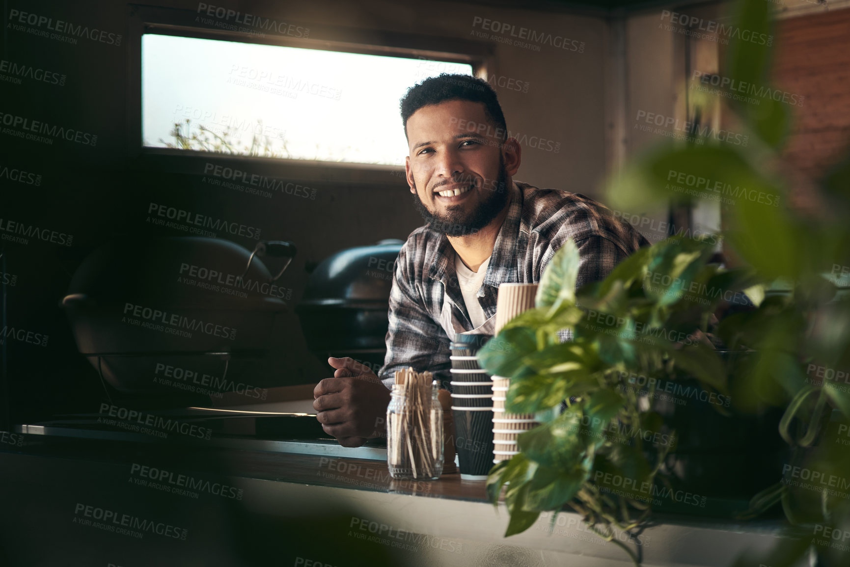 Buy stock photo Shot of a handsome young man standing alone inside his restaurant during the day