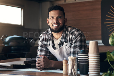 Buy stock photo Shot of a handsome young man standing alone inside his restaurant during the day