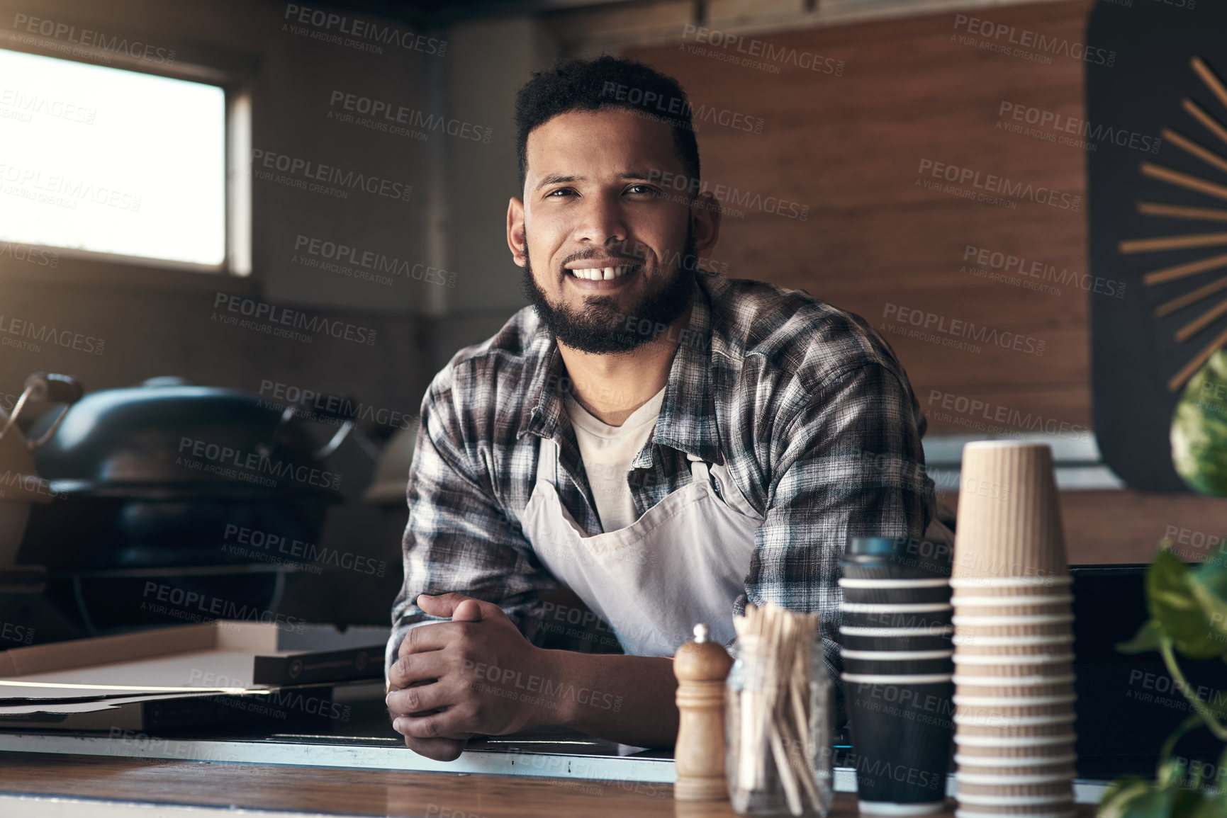 Buy stock photo Shot of a handsome young man standing alone inside his restaurant during the day