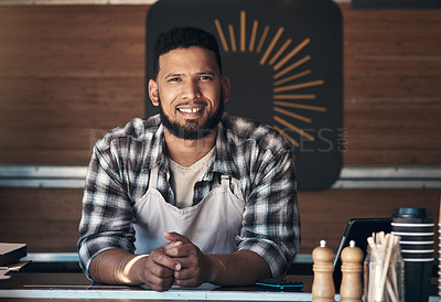 Buy stock photo Shot of a handsome young man standing alone inside his restaurant during the day