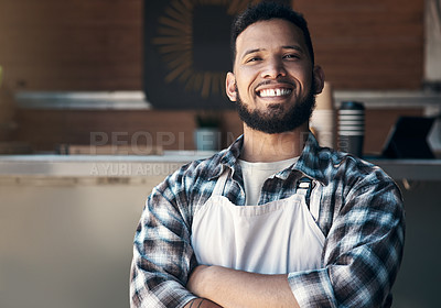 Buy stock photo Shot of a handsome young man standing with his arms folded inside his restaurant during the day