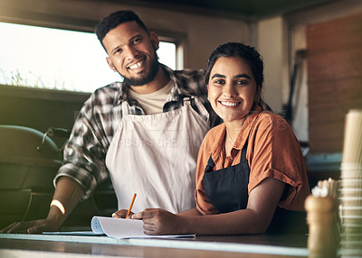 Buy stock photo Shot of two young restaurant owners standing inside together and planning their menu
