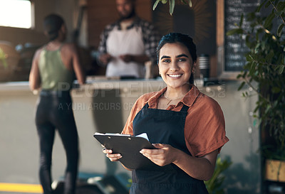 Buy stock photo Shot of an attractive young woman standing outside her restaurant and holding a clipboard