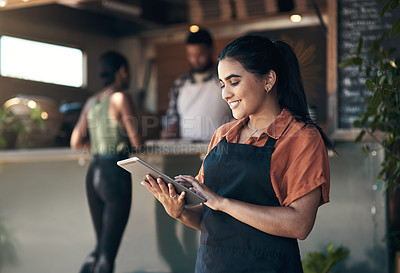Buy stock photo Shot of an attractive young woman standing outside her restaurant and using a digital tablet