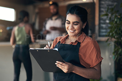 Buy stock photo Shot of an attractive young woman standing outside her restaurant and holding a clipboard