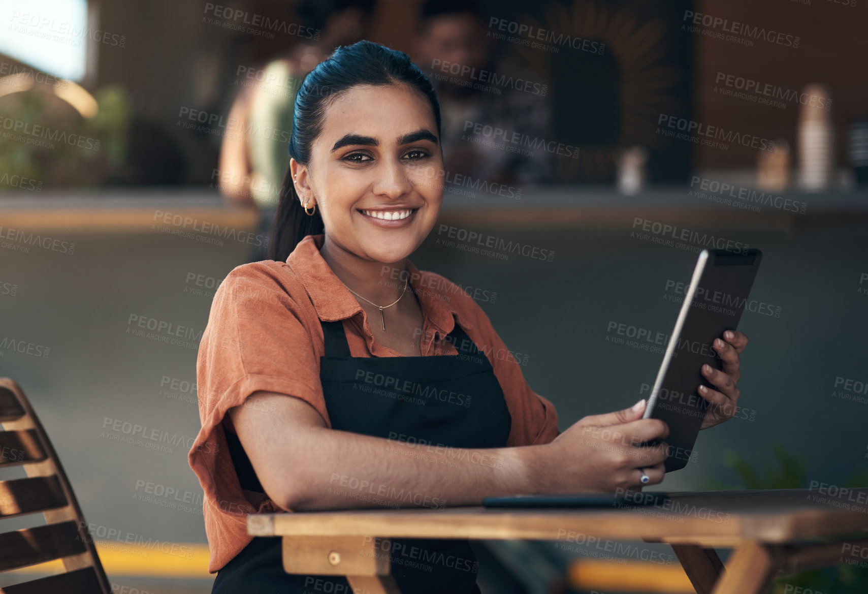 Buy stock photo Shot of an attractive young woman sitting outside her restaurant and using a digital tablet