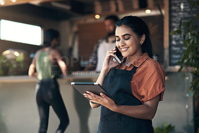 Buy stock photo Shot of an attractive young woman standing outside her restaurant and using technology to take orders