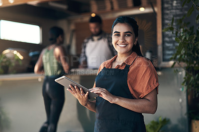 Buy stock photo Shot of an attractive young woman standing outside her restaurant and using a digital tablet