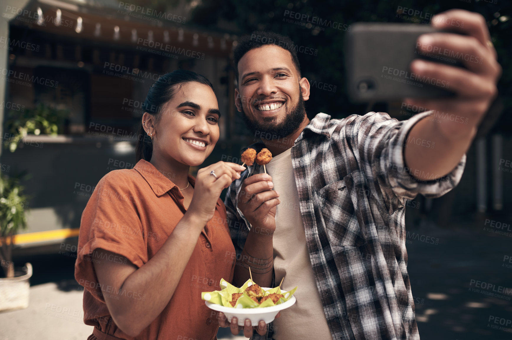 Buy stock photo Shot of two young friends standing outside a restaurant and using a cellphone to take a selfie