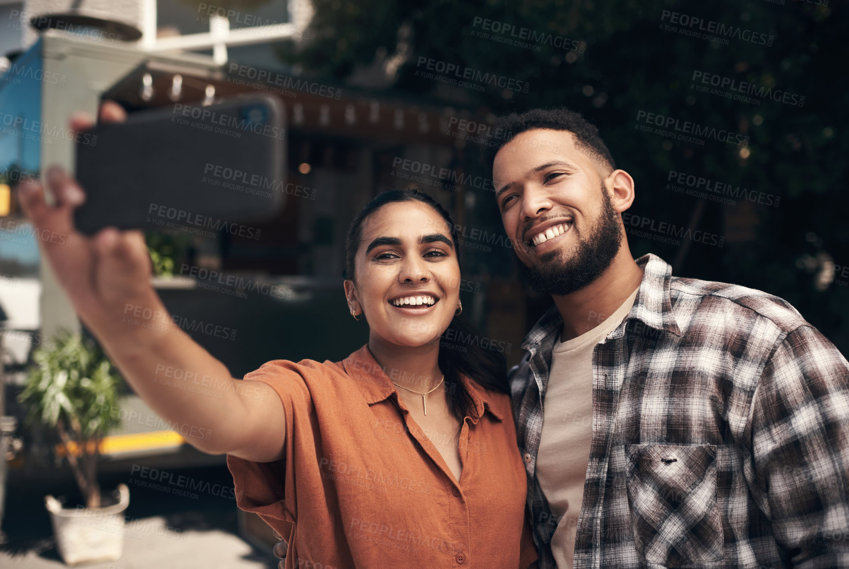 Buy stock photo Shot of two young friends standing outside a restaurant and using a cellphone to take a selfie