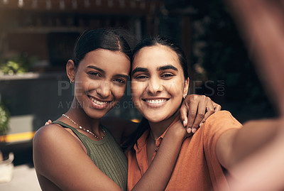 Buy stock photo Shot of two young friends standing outside a restaurant and taking selfies