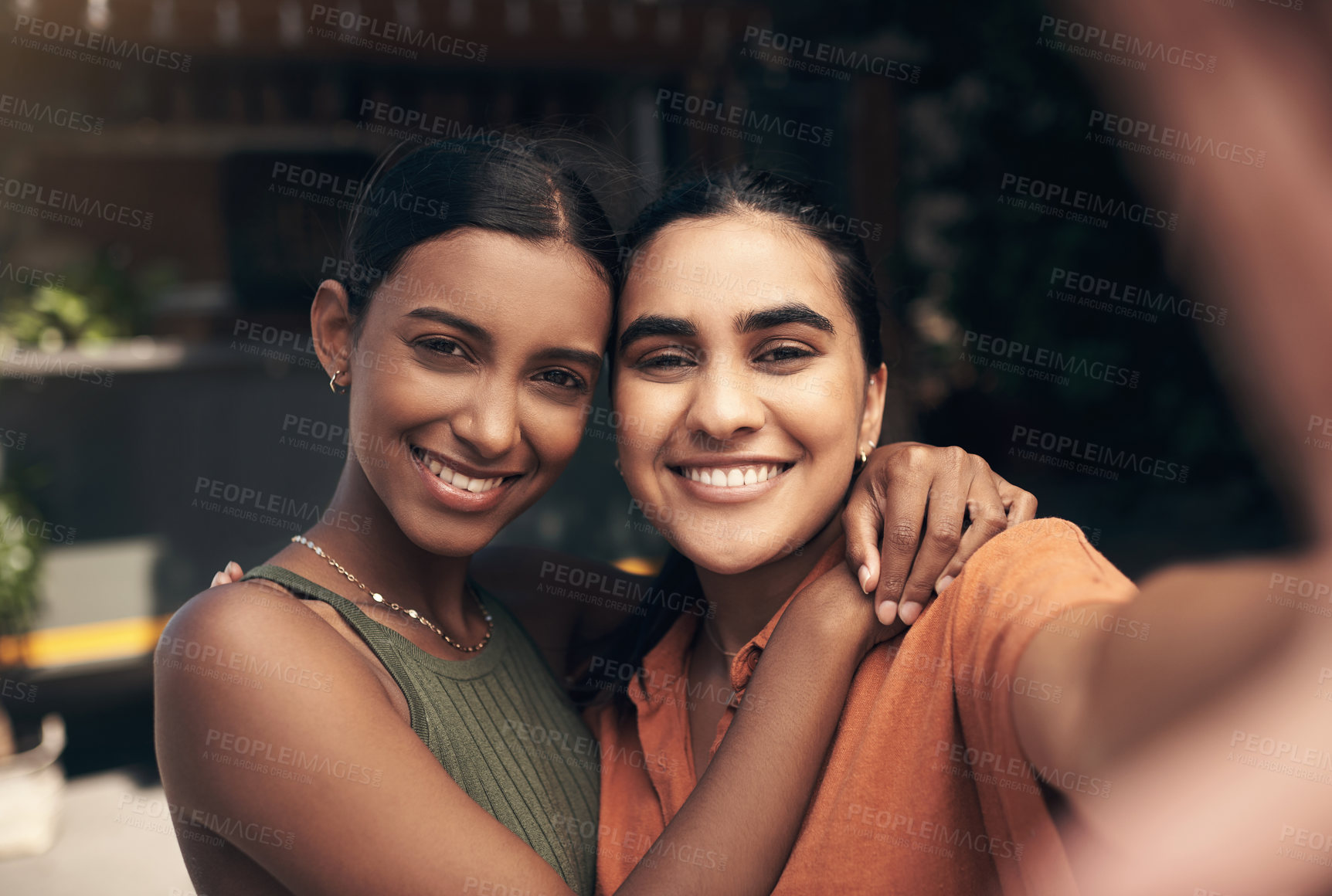 Buy stock photo Shot of two young friends standing outside a restaurant and taking selfies