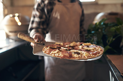 Buy stock photo Cropped shot of an unrecognizable man standing alone and holding a freshly made pizza in his restaurant