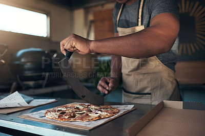 Buy stock photo Cropped shot of an unrecognizable man standing and preparing a freshly made pizza for takeaway in his restaurant