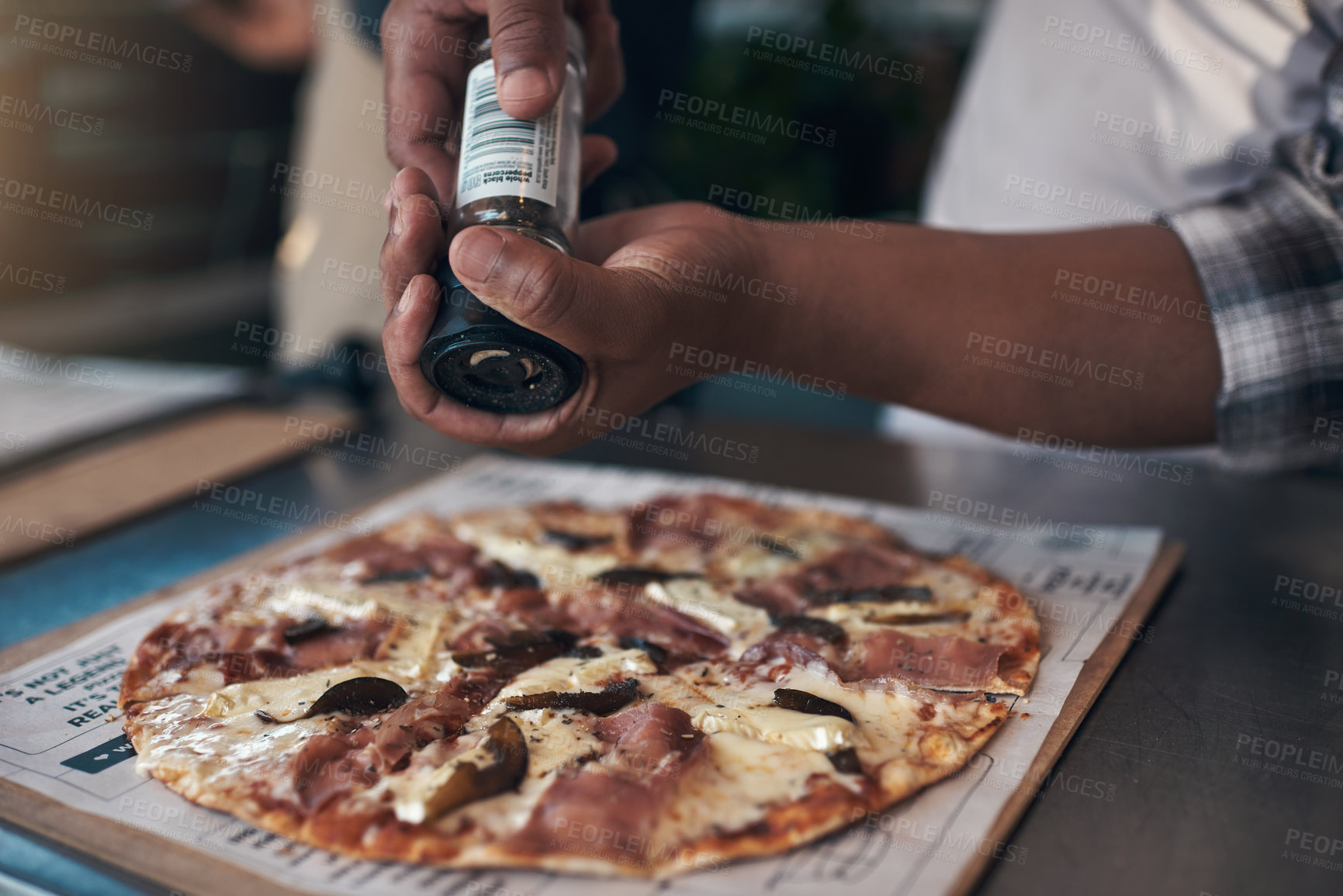 Buy stock photo Cropped shot of an unrecognizable man standing and preparing a freshly made pizza for takeaway in his restaurant