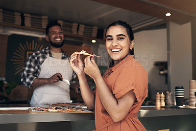 Buy stock photo Shot of an attractive young woman standing and enjoying a freshly made pizza at a restaurant