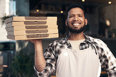 Buy stock photo Shot of a handsome young man standing outside his restaurant and holding a stack of pizza boxes