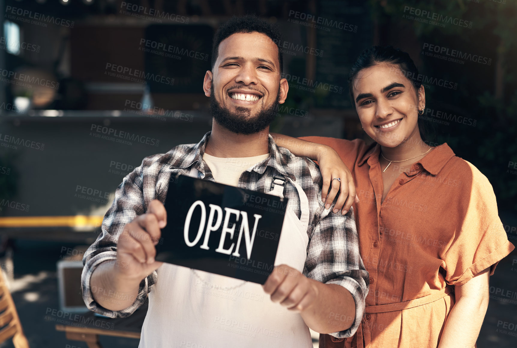 Buy stock photo Shot of two young restaurant owners standing outside together and holding an open sign