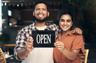 Buy stock photo Shot of two young restaurant owners standing outside together and holding an open sign
