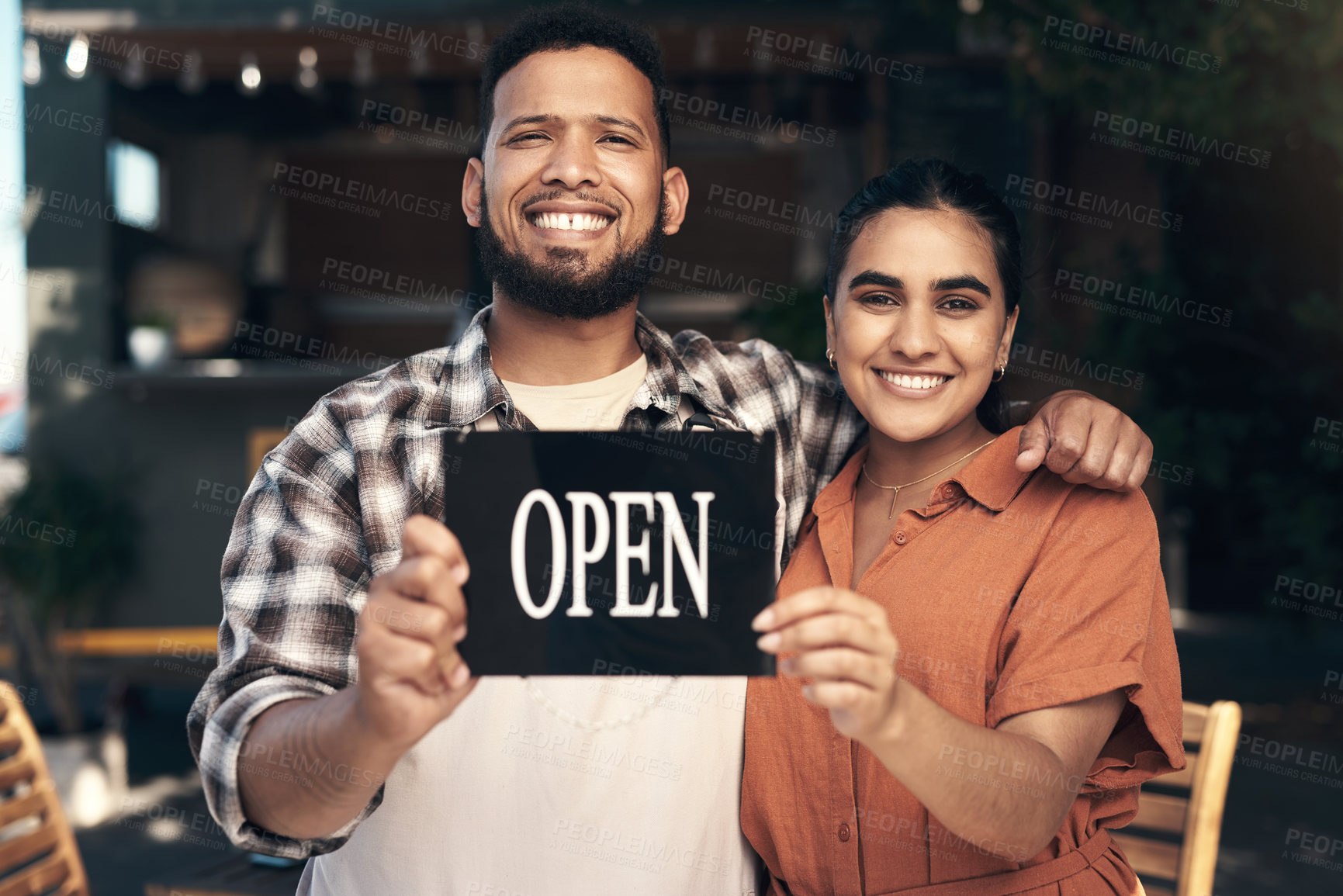 Buy stock photo Shot of two young restaurant owners standing outside together and holding an open sign