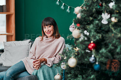 Buy stock photo Portrait o a young an attractive woman relaxing on the sofa next to a Christmas tree at home