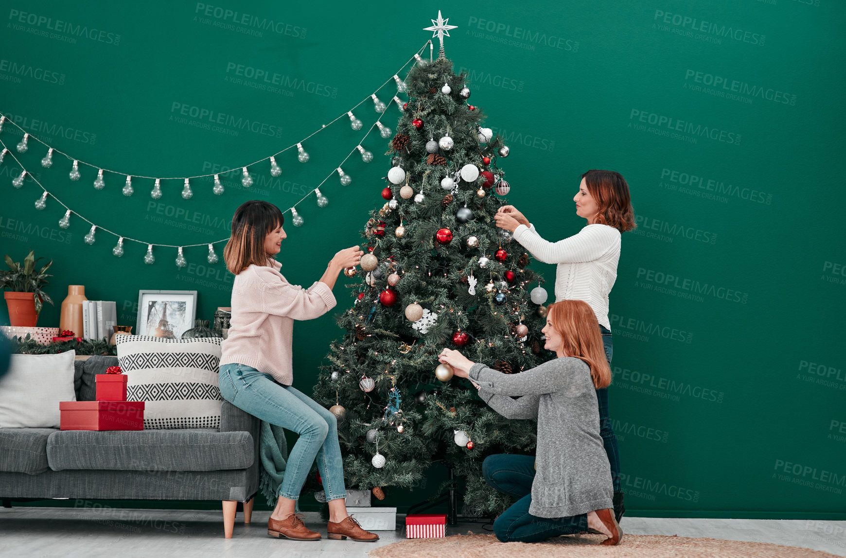 Buy stock photo Women, decor and Christmas tree in living room for interior, bonding and season happiness in lounge. Xmas ornaments, holiday and friends by couch for fun, celebration and tradition in winter