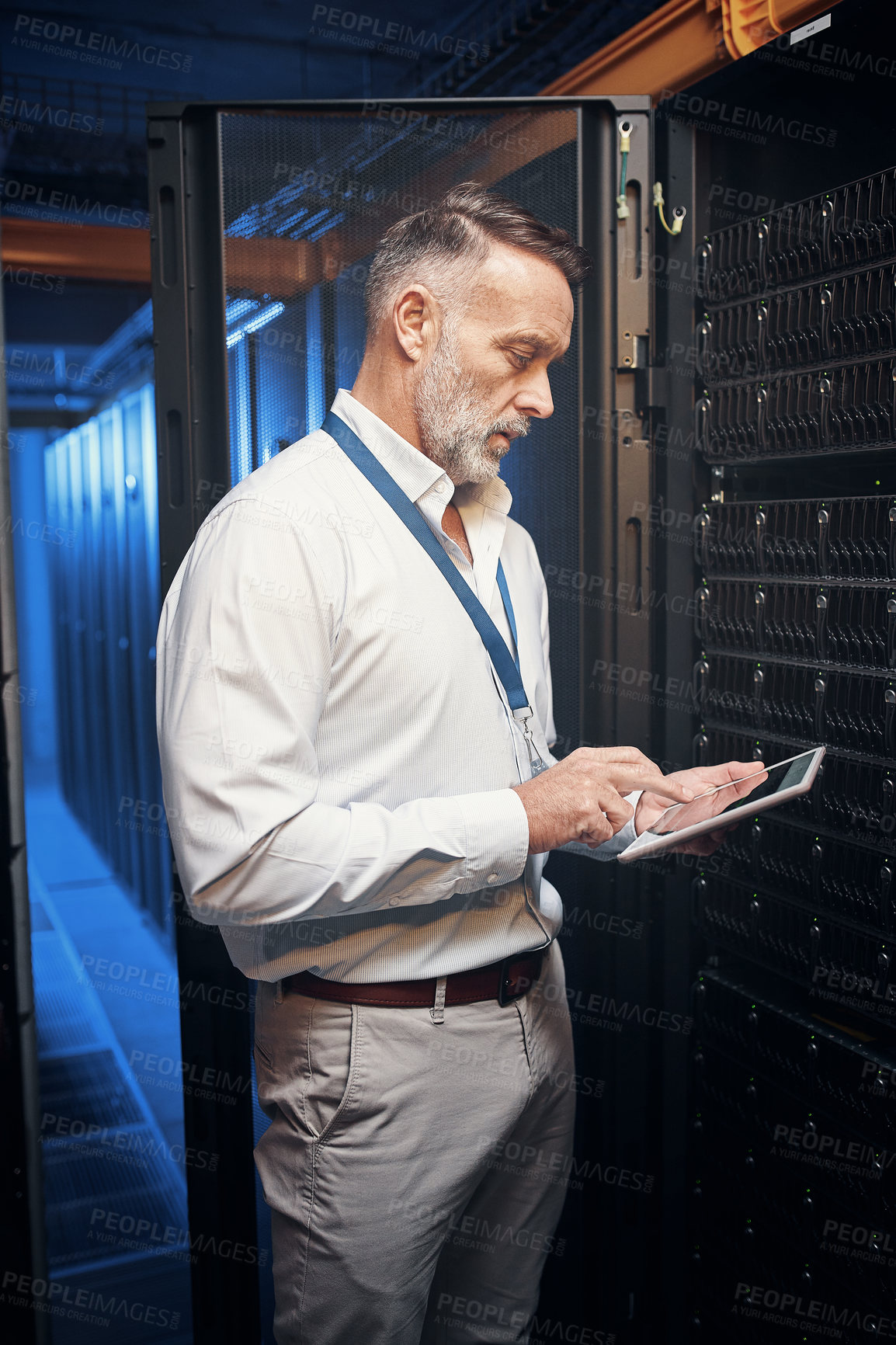 Buy stock photo Shot of a mature man using a digital tablet while working in a server room