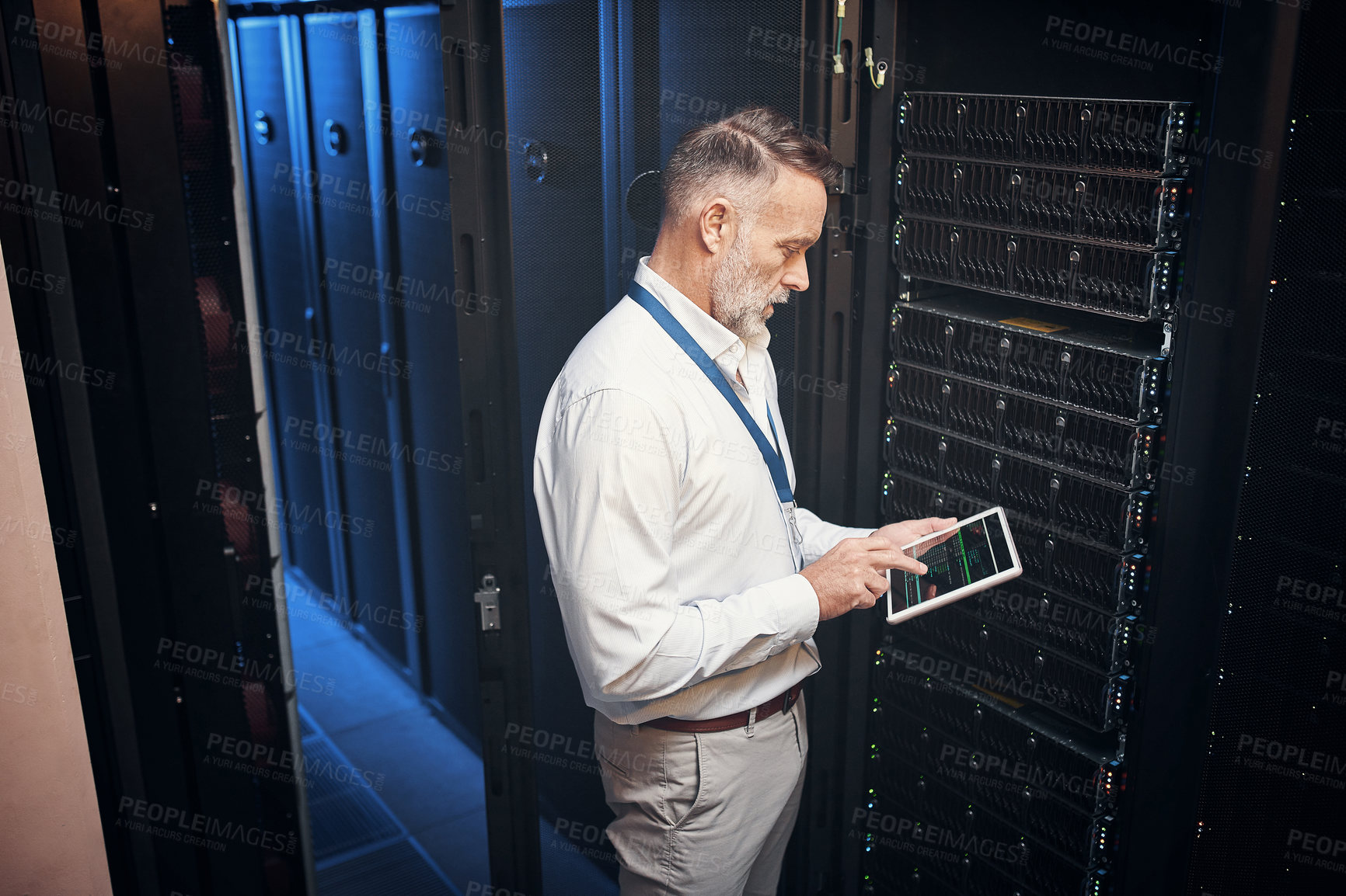 Buy stock photo Shot of a mature man using a digital tablet while working in a server room