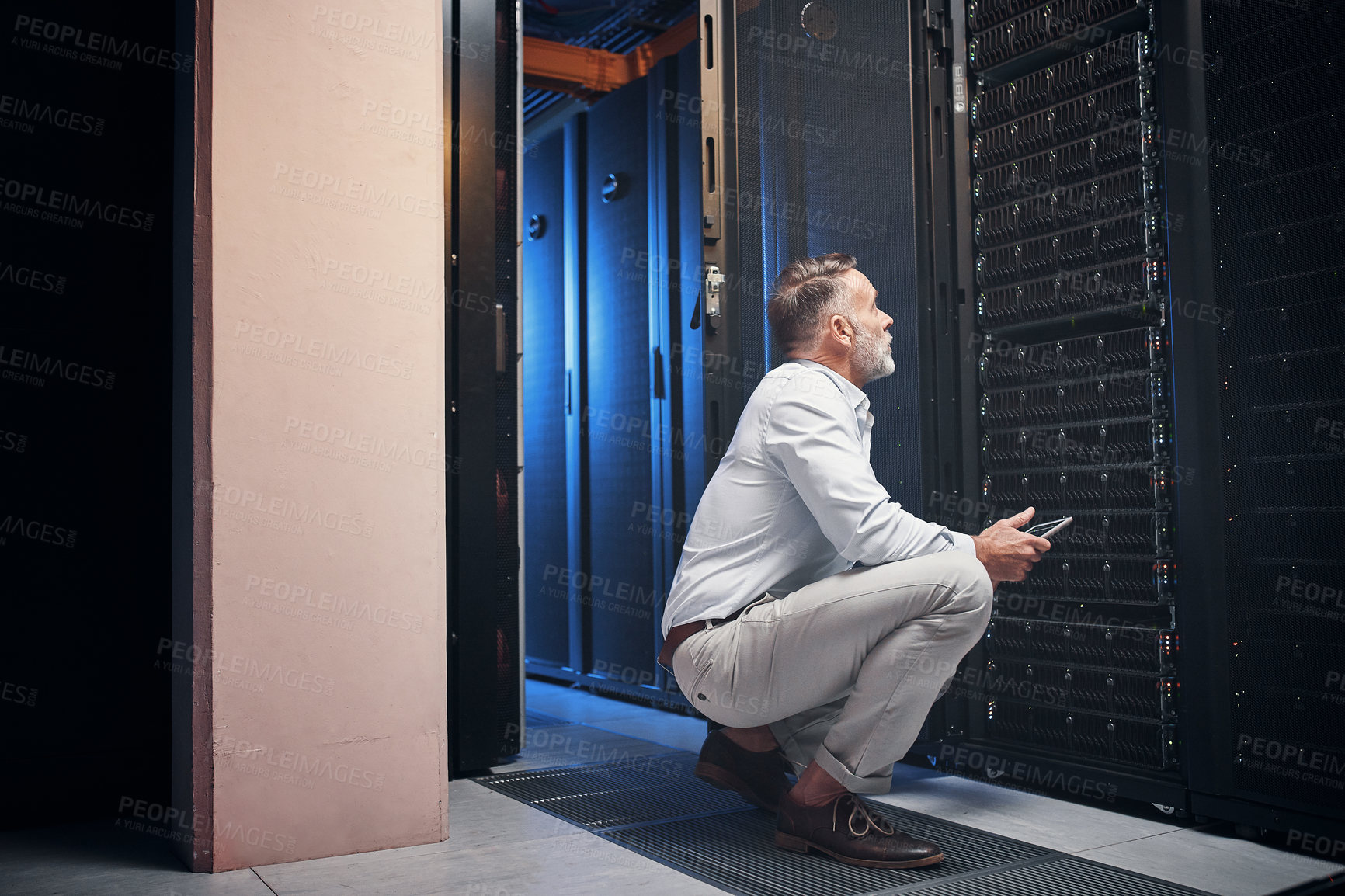 Buy stock photo Shot of a mature man using a digital tablet while working in a server room