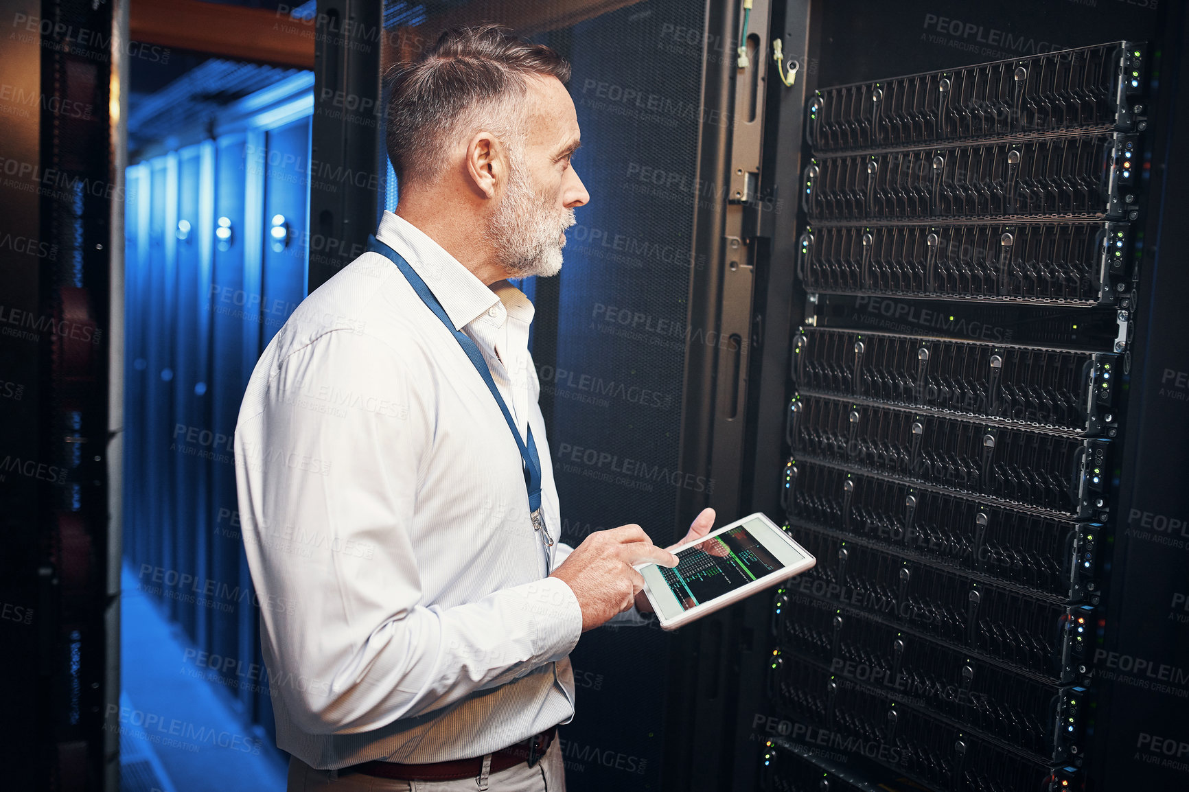 Buy stock photo Shot of a mature man using a digital tablet while working in a server room