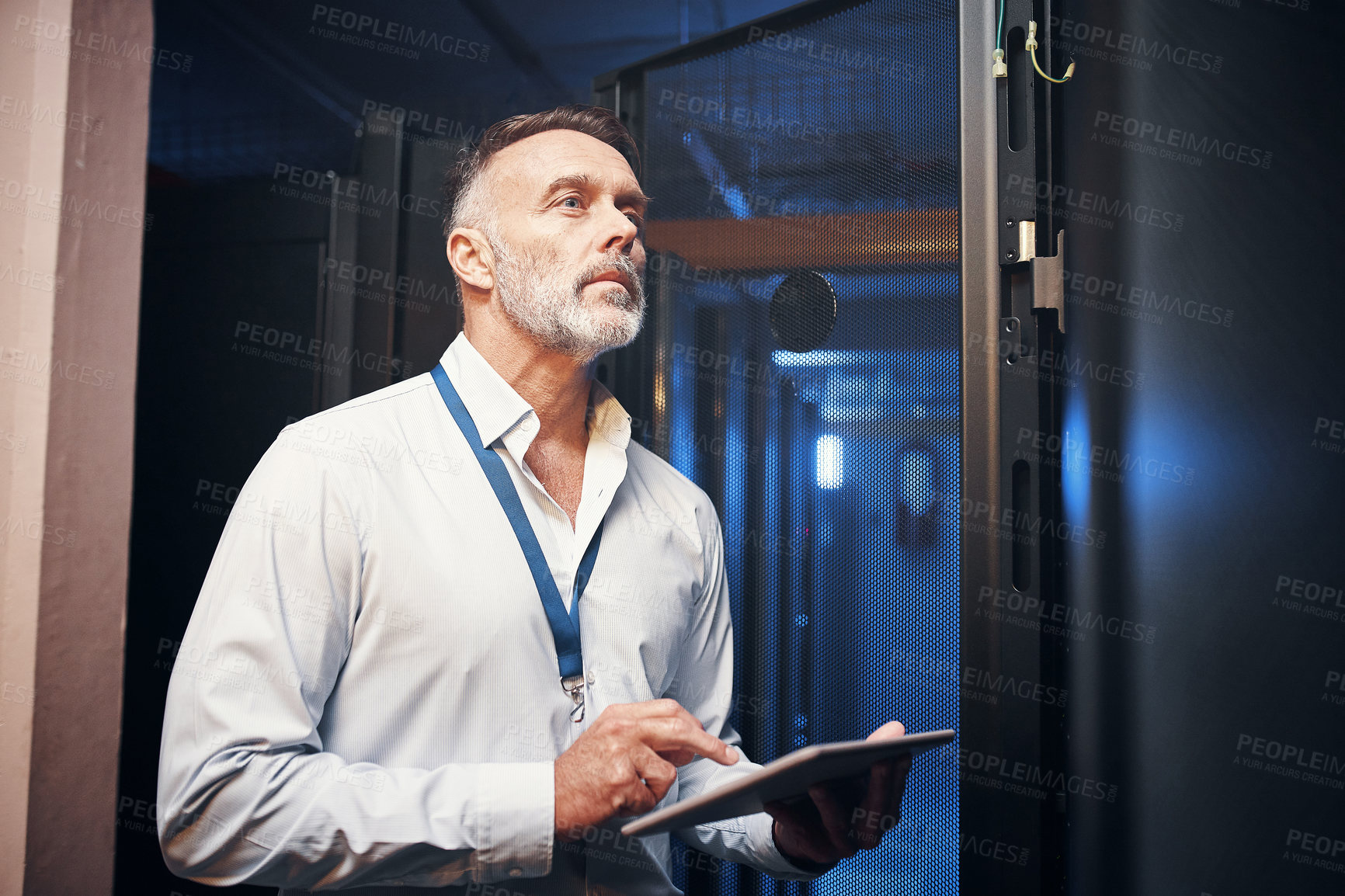 Buy stock photo Shot of a mature man using a digital tablet while working in a server room