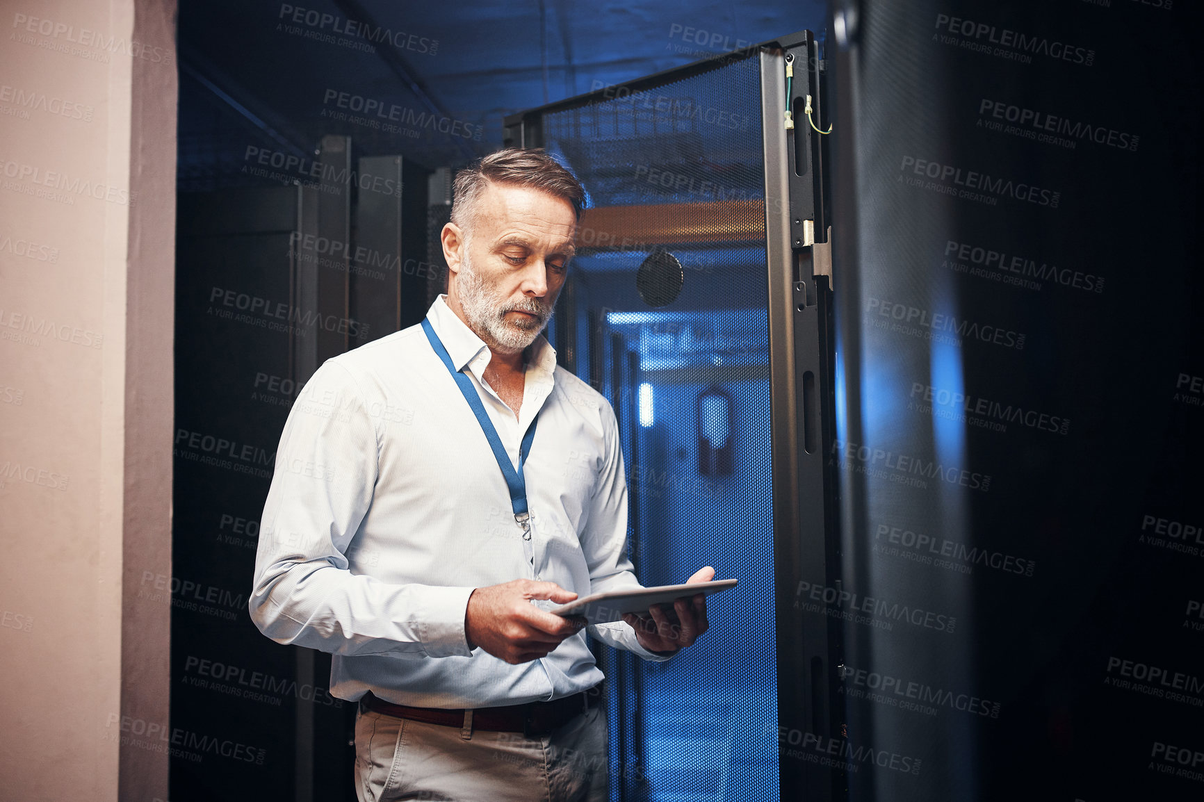 Buy stock photo Shot of a mature man using a digital tablet while working in a server room