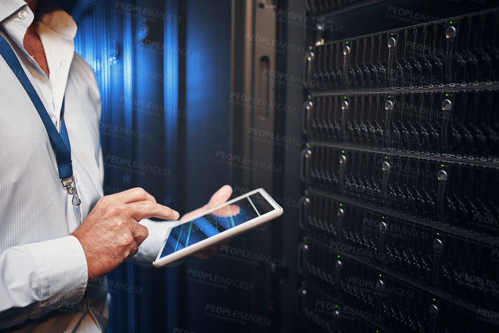 Buy stock photo Shot of an unrecognisable man using a digital tablet while working in a server room